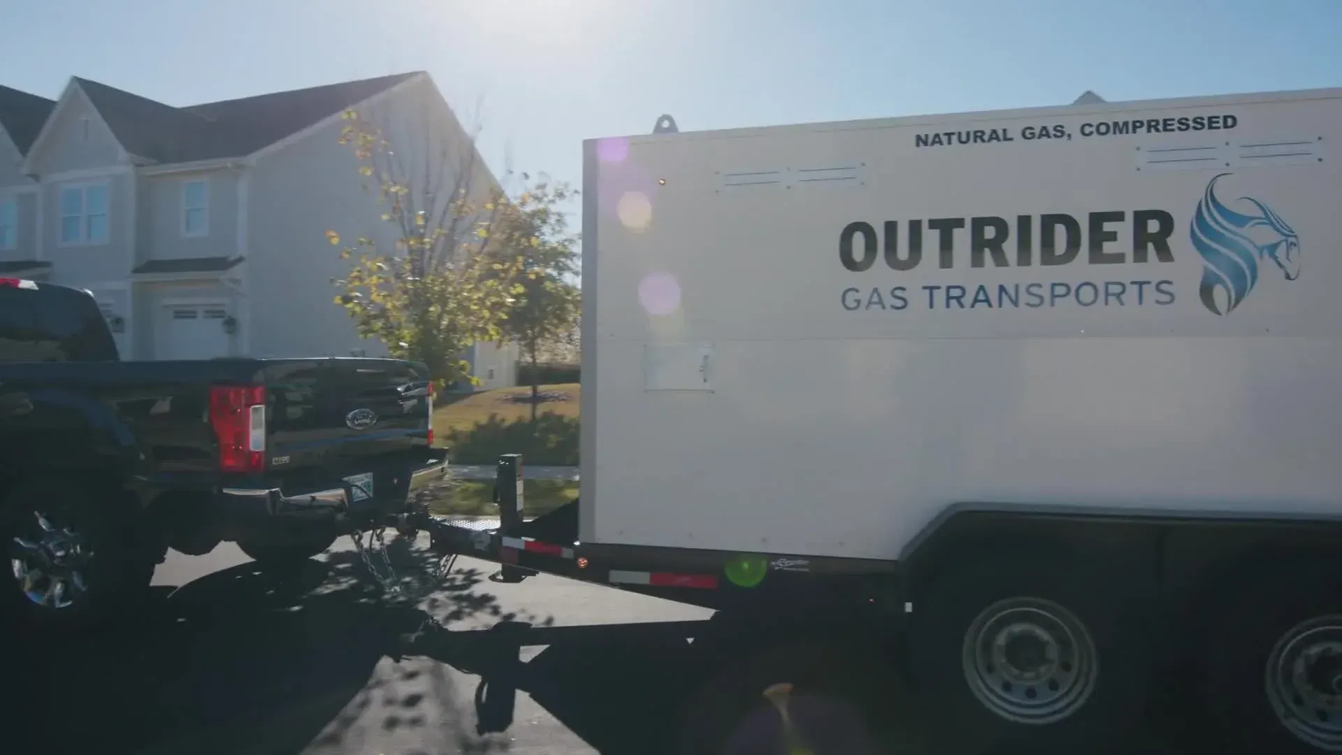 White gas transport truck with OUTRIDER logo parked in a sunny residential driveway