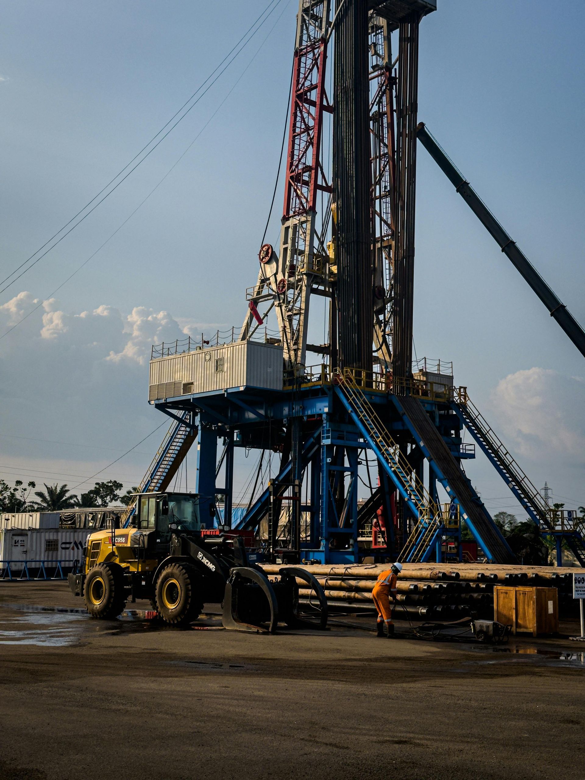 Industrial drilling rig on a flatbed trailer at a construction site, with mountains in the background.
