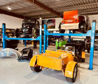 Bright orange and blue custom vehicles on metal lifts in a workshop garage