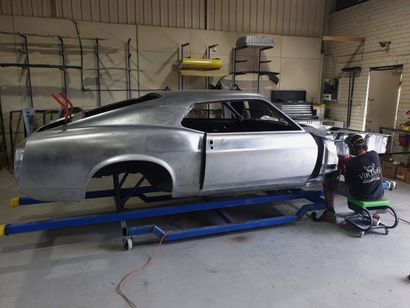 Silver classic car body on a blue frame in a workshop