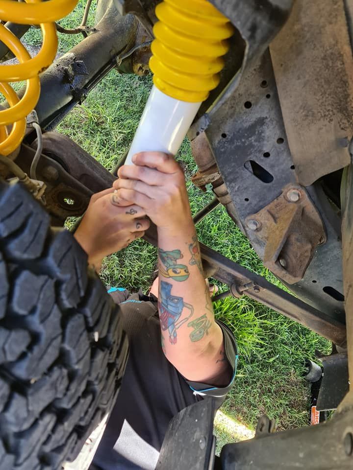 A Person With A Tattoo On Their Arm Is Working On A Truck — M8S Rates Mechanical In Gladstone Central, QLD