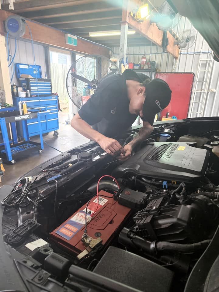 A Man Is Working On The Engine Of A Car In A Garage — M8S Rates Mechanical In Gladstone Central, QLD