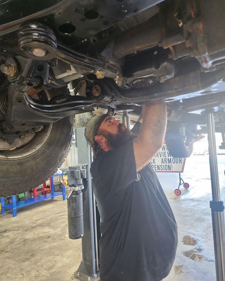 A Man Is Working Underneath A Car In A Garage — M8S Rates Mechanical In Gladstone Central, QLD