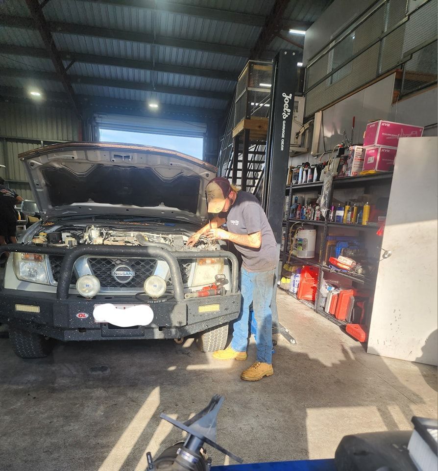 A Man Is Working On A Nissan Truck In A Garage — M8S Rates Mechanical In Gladstone Central, QLD