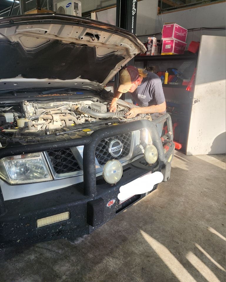 A Man Is Working On The Engine Of A Car In A Garage — M8S Rates Mechanical In Gladstone Central, QLD