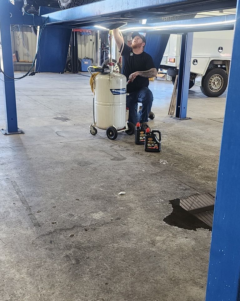 A Man Is Sitting Under A Car On A Lift In A Garage — M8S Rates Mechanical In Gladstone Central, QLD