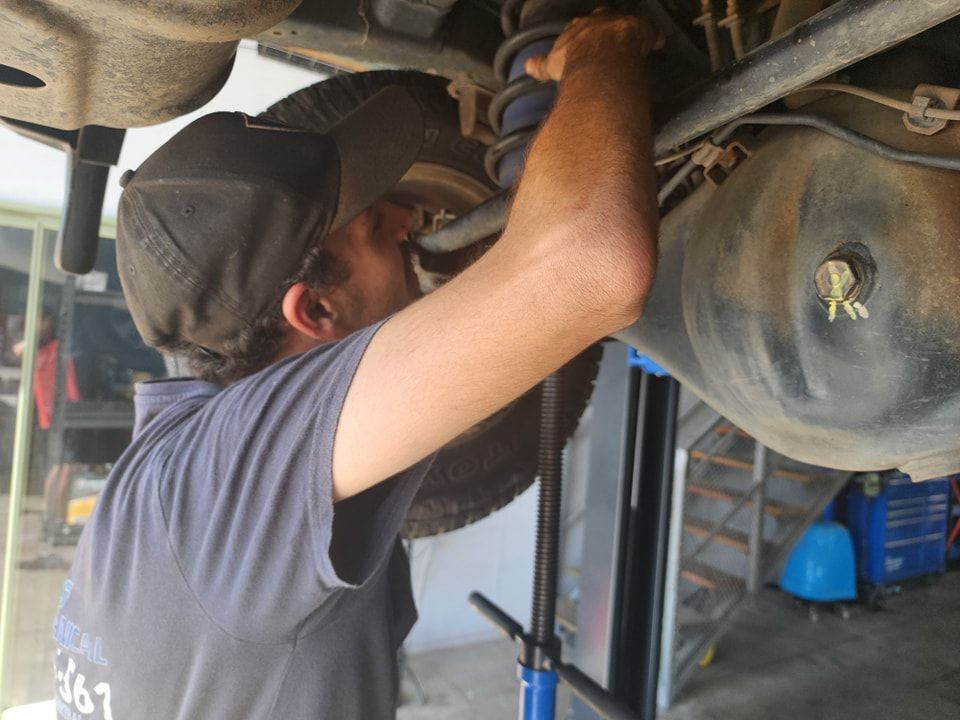 A Man Is Working On The Underside Of A Car — M8S Rates Mechanical In Gladstone Central, QLD