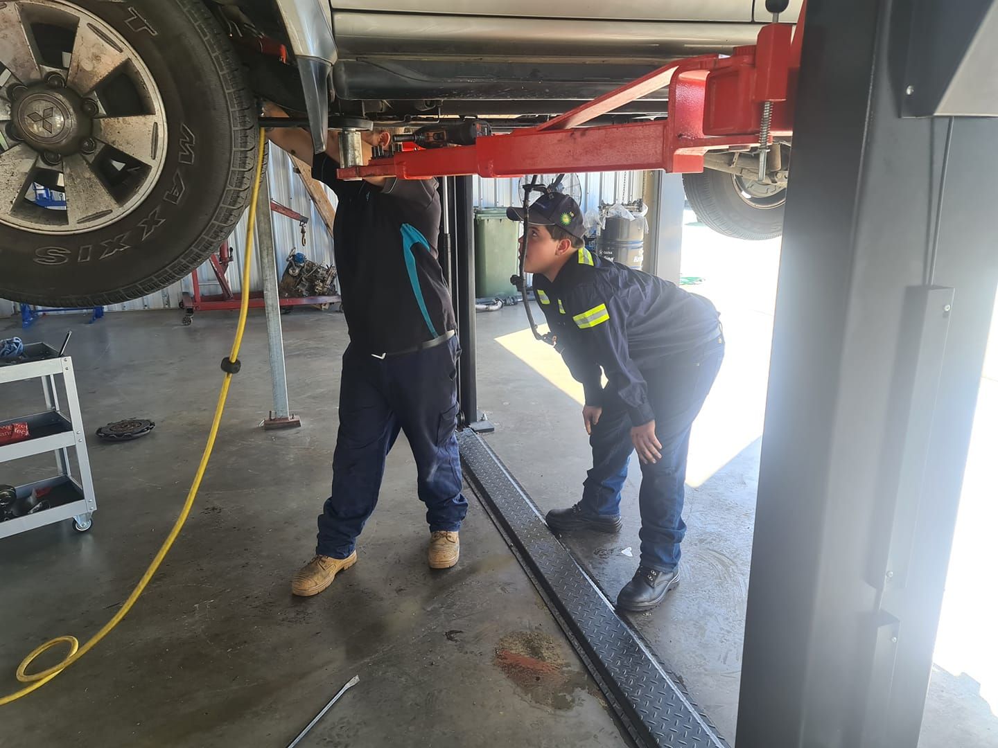 Two Men Are Working On A Car On A Lift In A Garage — M8S Rates Mechanical In Gladstone Central, QLD