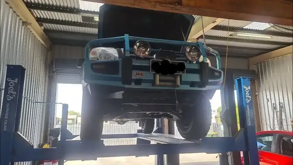 A Blue Truck Is Sitting On A Lift In A Garage — M8S Rates Mechanical In Gladstone Central, QLD