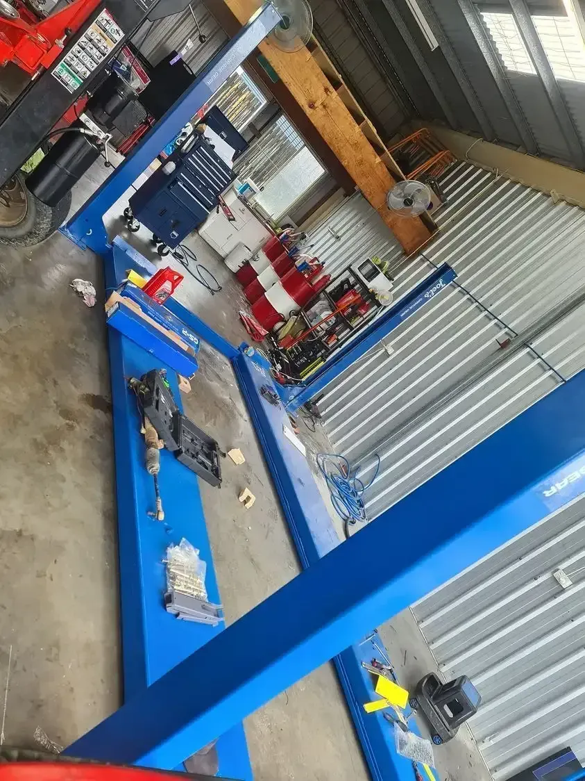A Blue Lift Is Sitting In A Garage Next To A Red Forklift — M8S Rates Mechanical In Gladstone Central, QLD