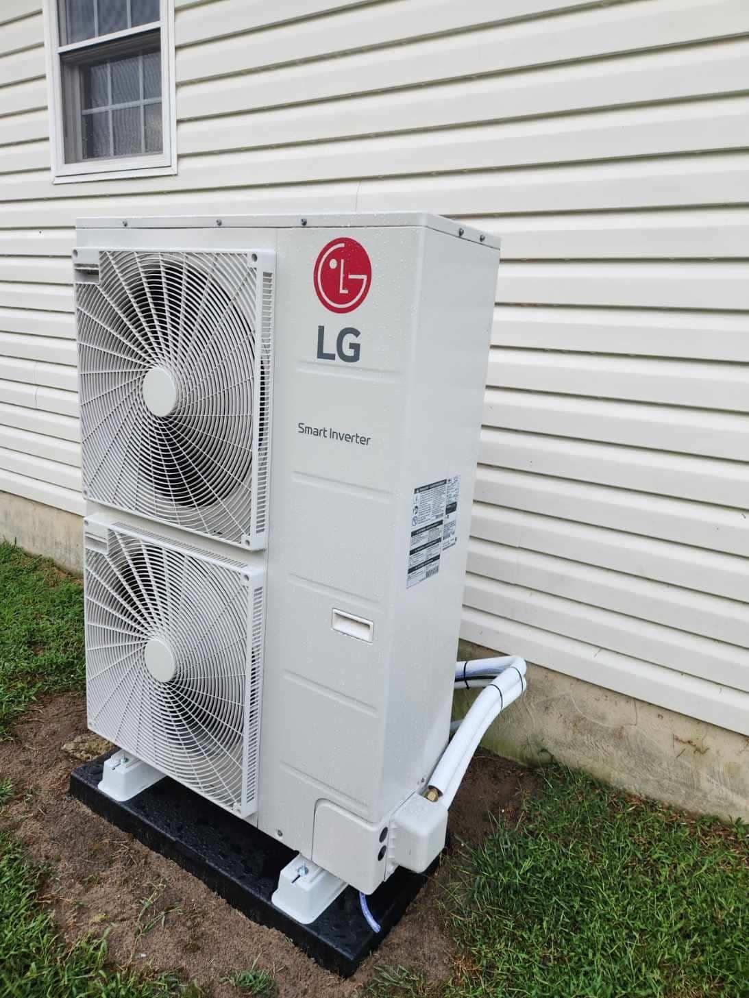 LG mini-split outdoor AC unit beside a house, with dual fans on a black stand.