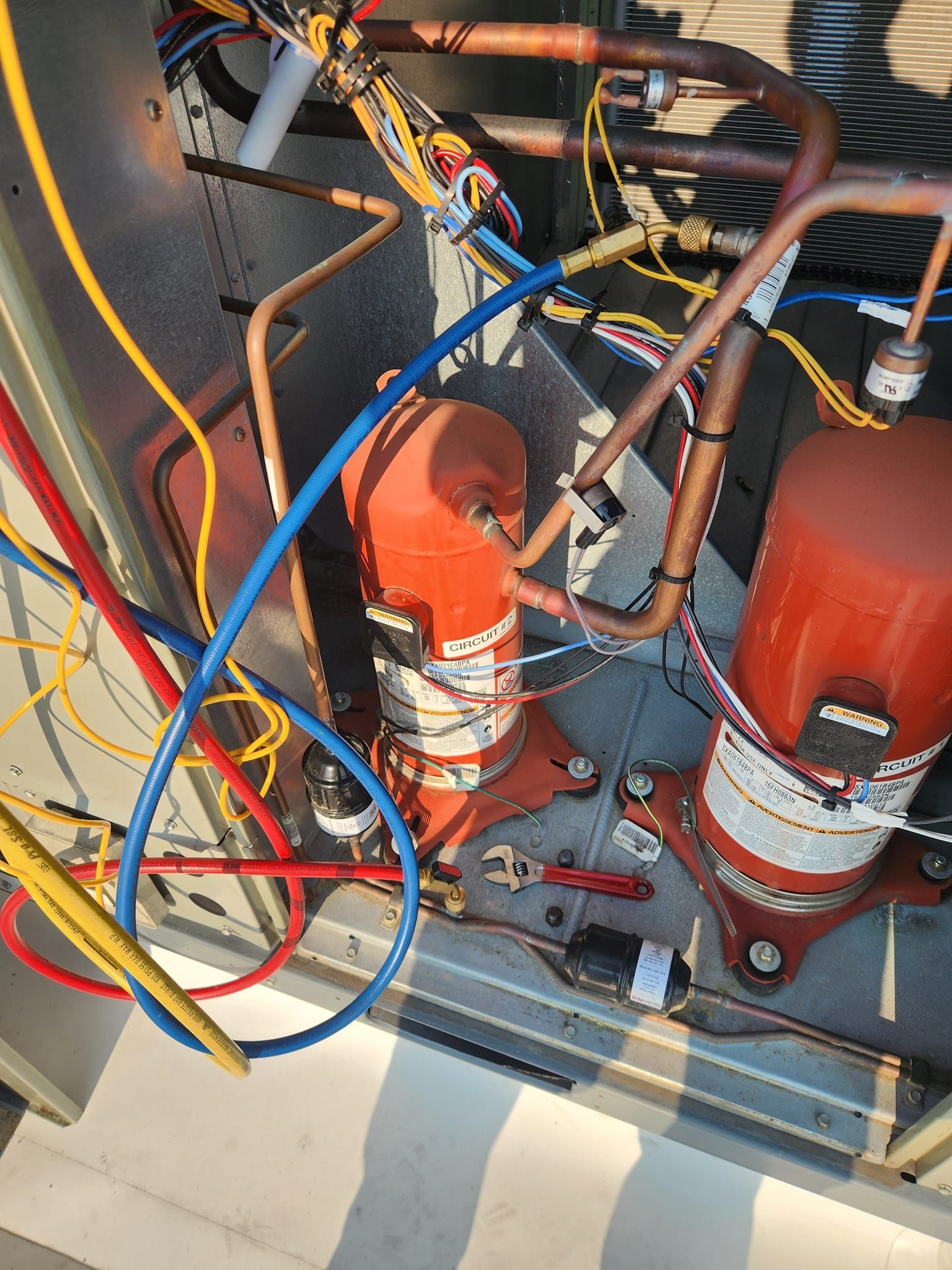 Red industrial pumps with tangled blue, yellow, and brown hoses inside a utility cabinet