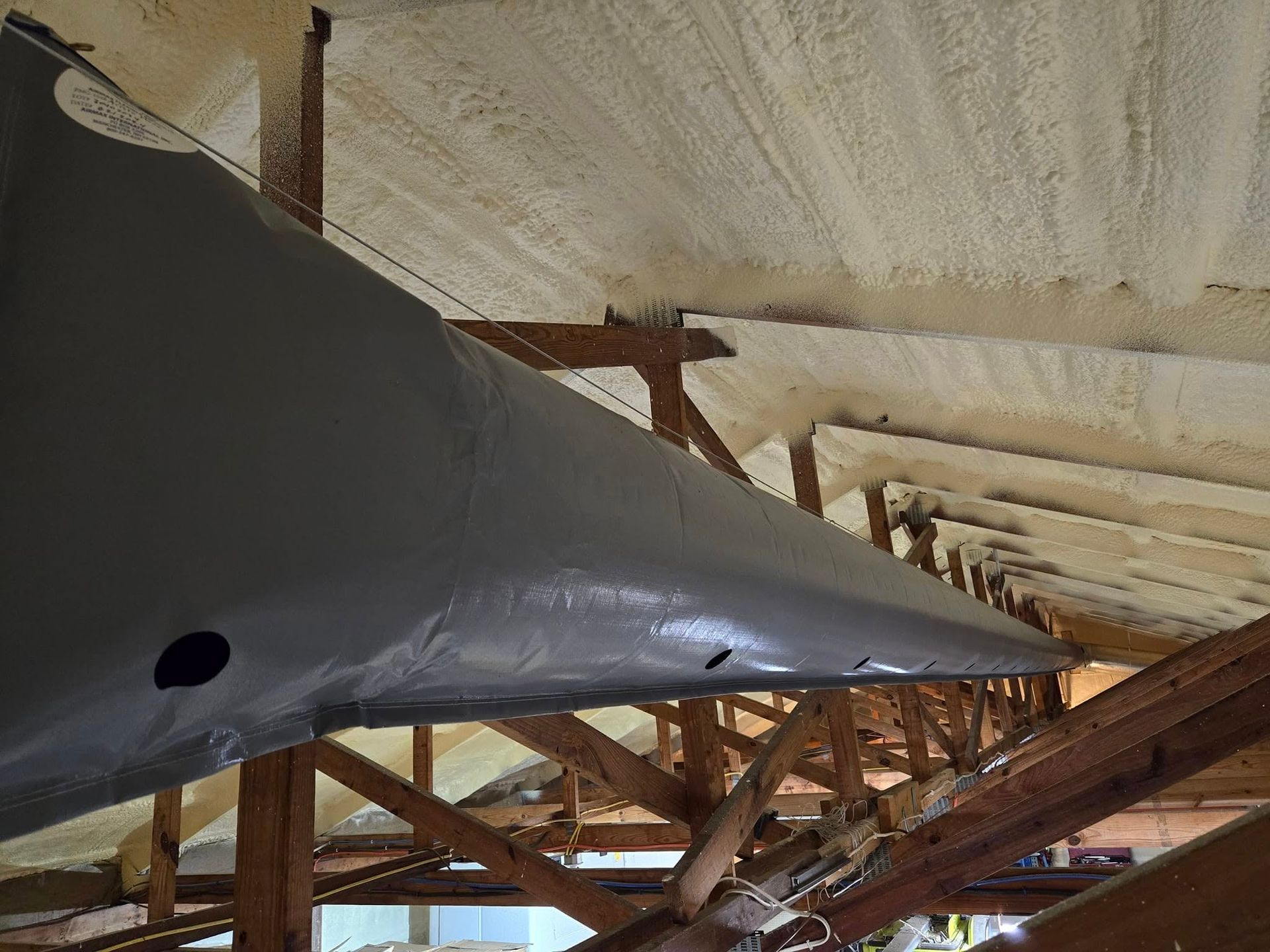 Gray boat hull under construction inside a wooden boat shed