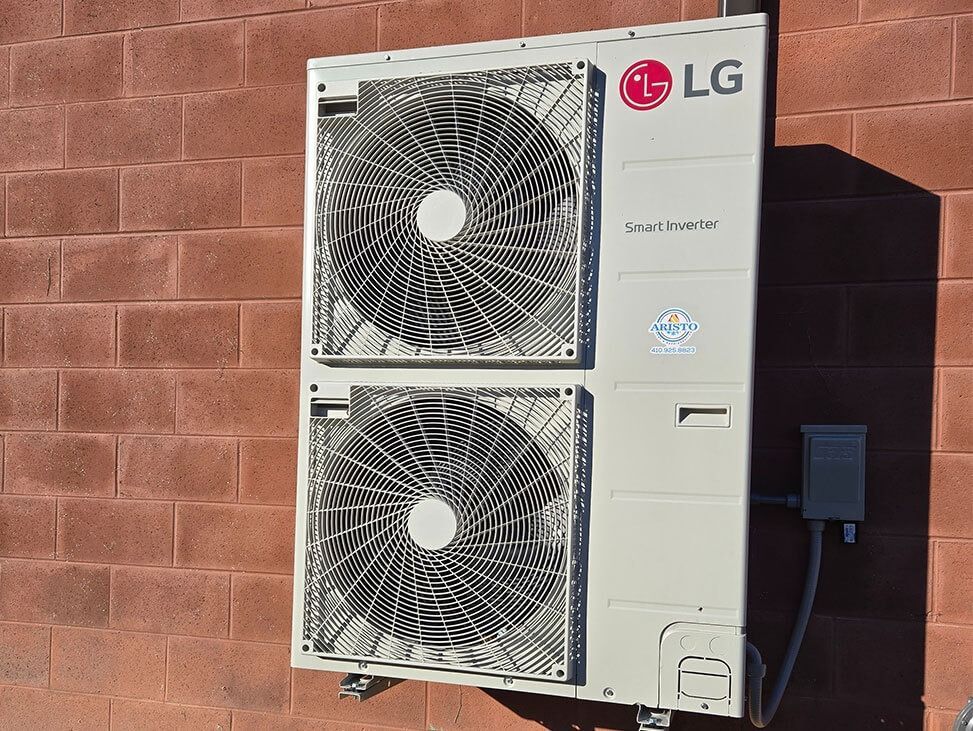 LG outdoor air conditioner unit with two large fans mounted on a brick wall.