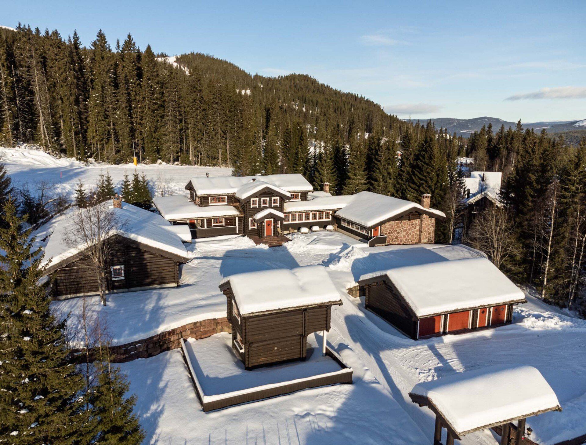 En gruppe hus dekket av snø midt i en snødekt skog.