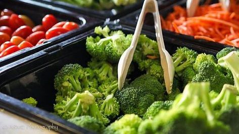 A buffet filled with broccoli , carrots , celery , tomatoes and other vegetables.