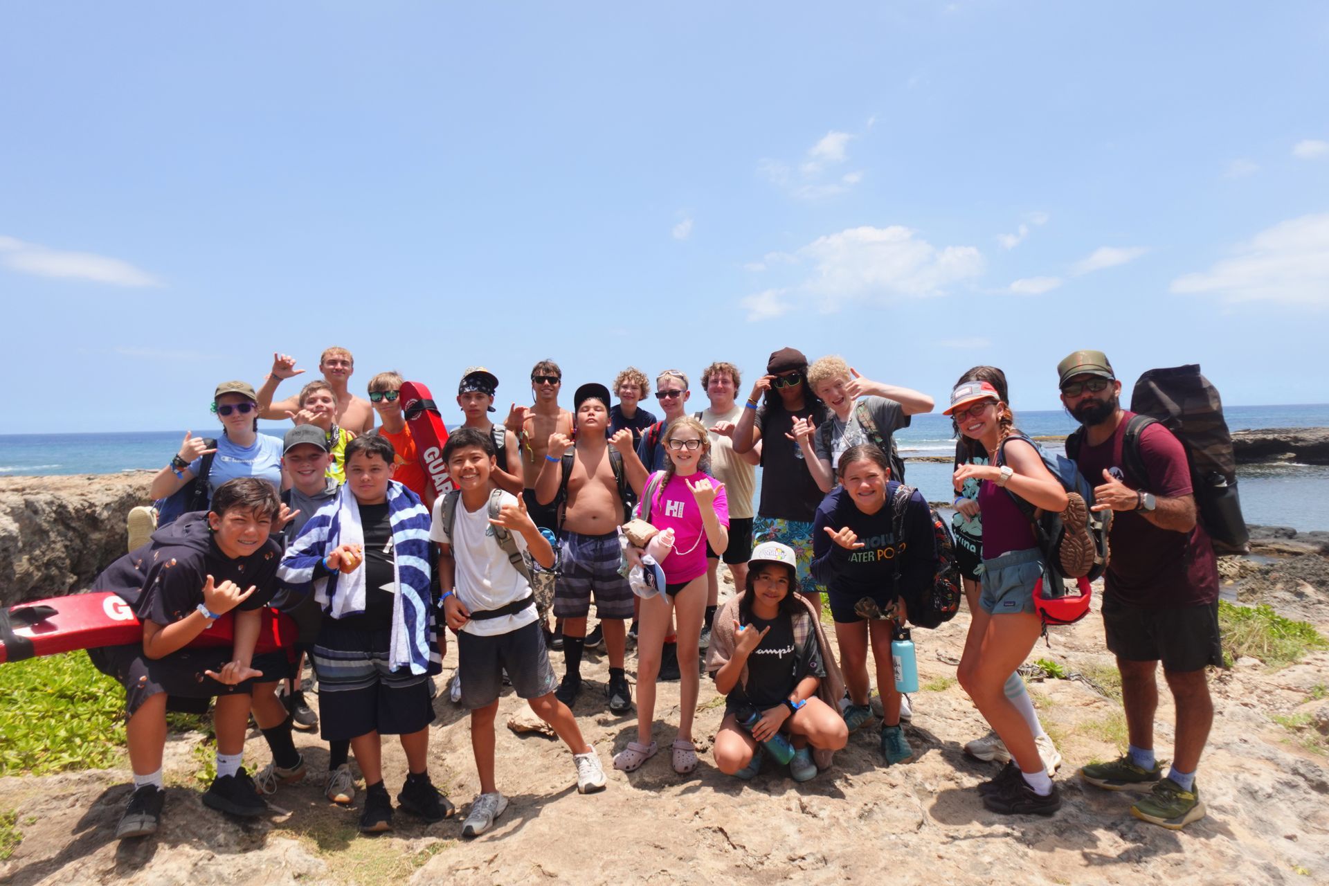 A group of people are posing for a picture on a beach.