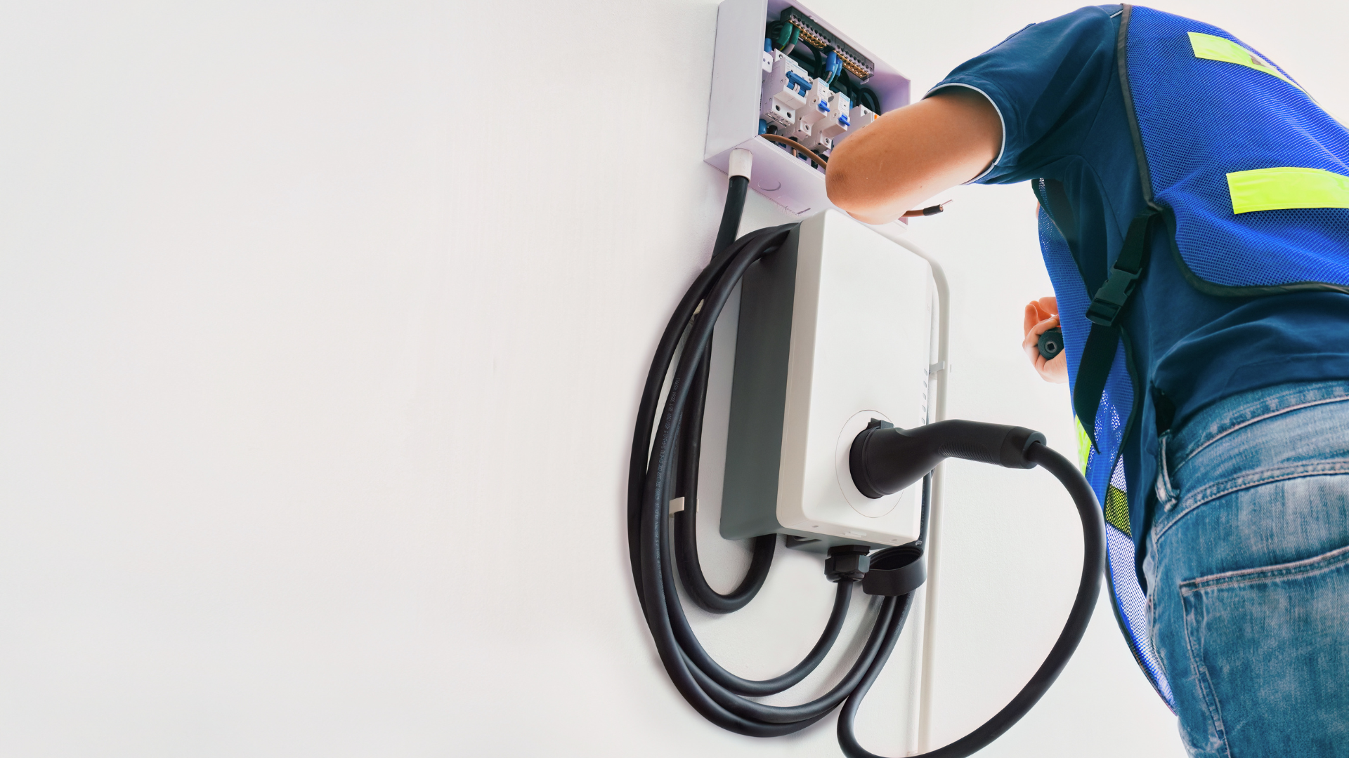 Technician installing a wall-mounted charging station with a coiled black cable