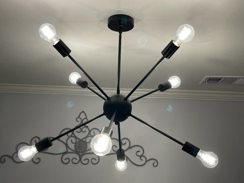 A black chandelier with many light bulbs hanging from the ceiling A black chandelier with many light bulbs hanging from the ceiling