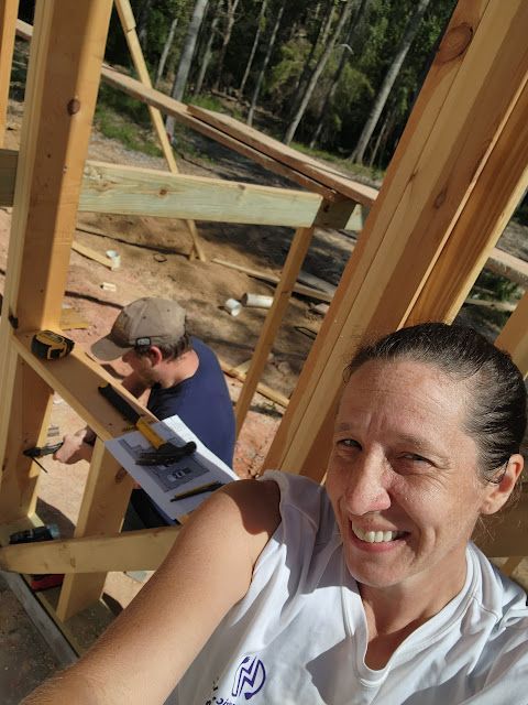 A woman is taking a selfie in front of a building under construction. A woman is taking a selfie in front of a building under construction.