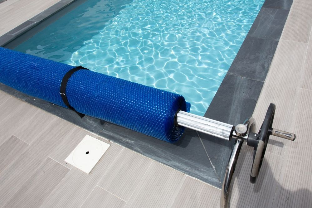 Blue Pool Cover Rolled on a Silver Reel Beside a Pool — Tempshift Pool Heating in Buff Point, NSW