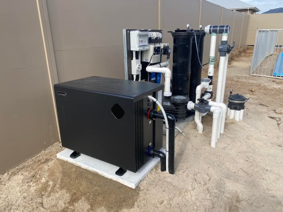 Black Pool Heat Pump, Filter, and Plumbing Against a Wall on a Concrete Pad — Tempshift Pool Heating in Buff Point, NSW