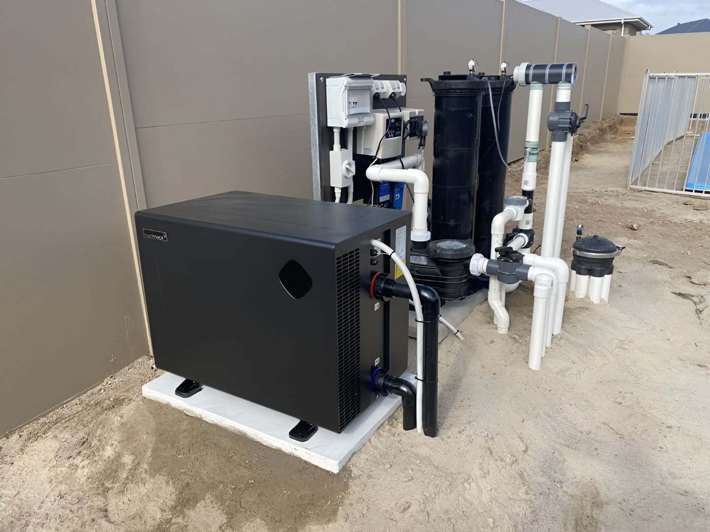 Black Pool Heat Pump Next to a Filter System Against a Grey Wall — Tempshift Pool Heating in Buff Point, NSW