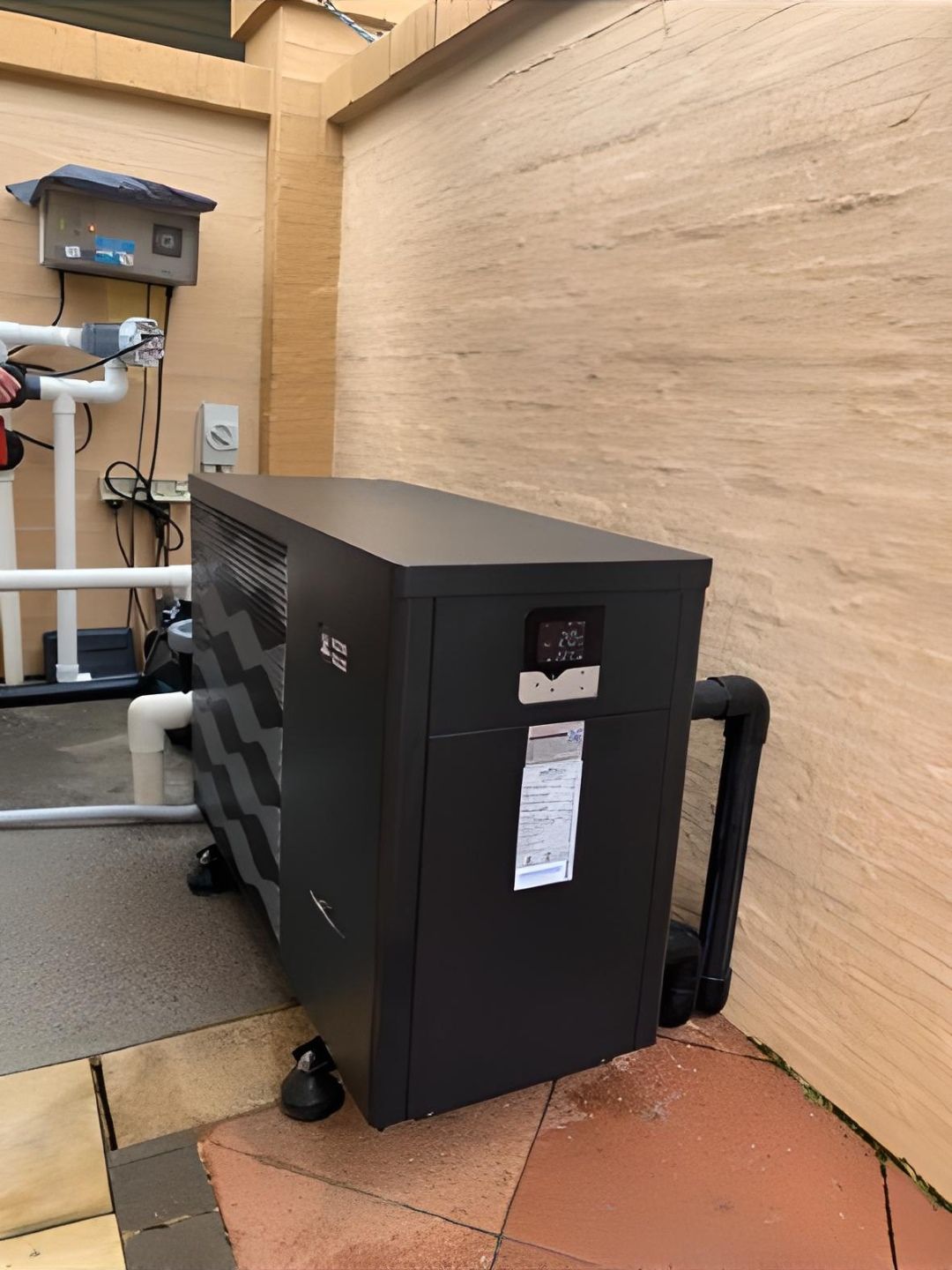 Black Pool Heater Against a Beige Wall With Pipes and Control Box Visible — Tempshift Pool Heating in Buff Point, NSW