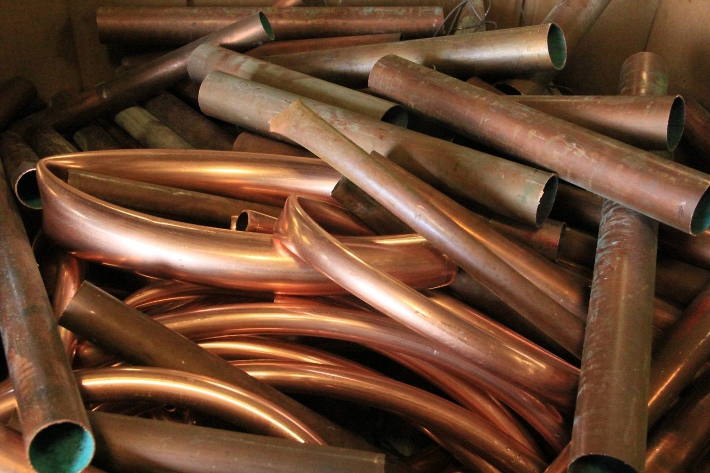 A pile of copper pipes sitting on top of each other in a box.