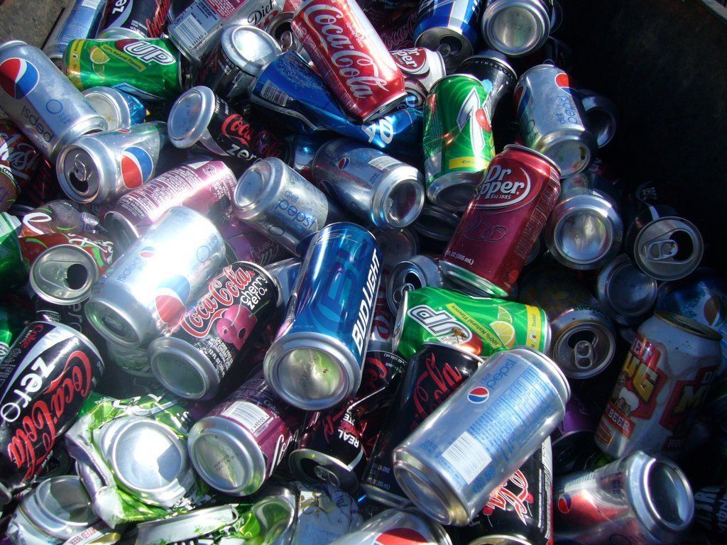 A pile of crushed soda cans including coca cola and pepsi.