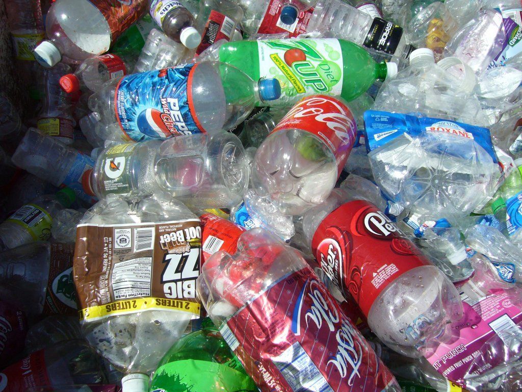A pile of plastic bottles including coca cola and 7 up.
