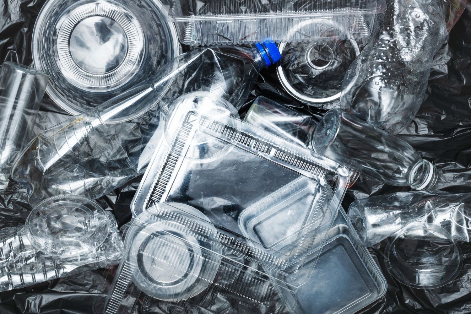 A pile of plastic bottles and containers in a trash bag.