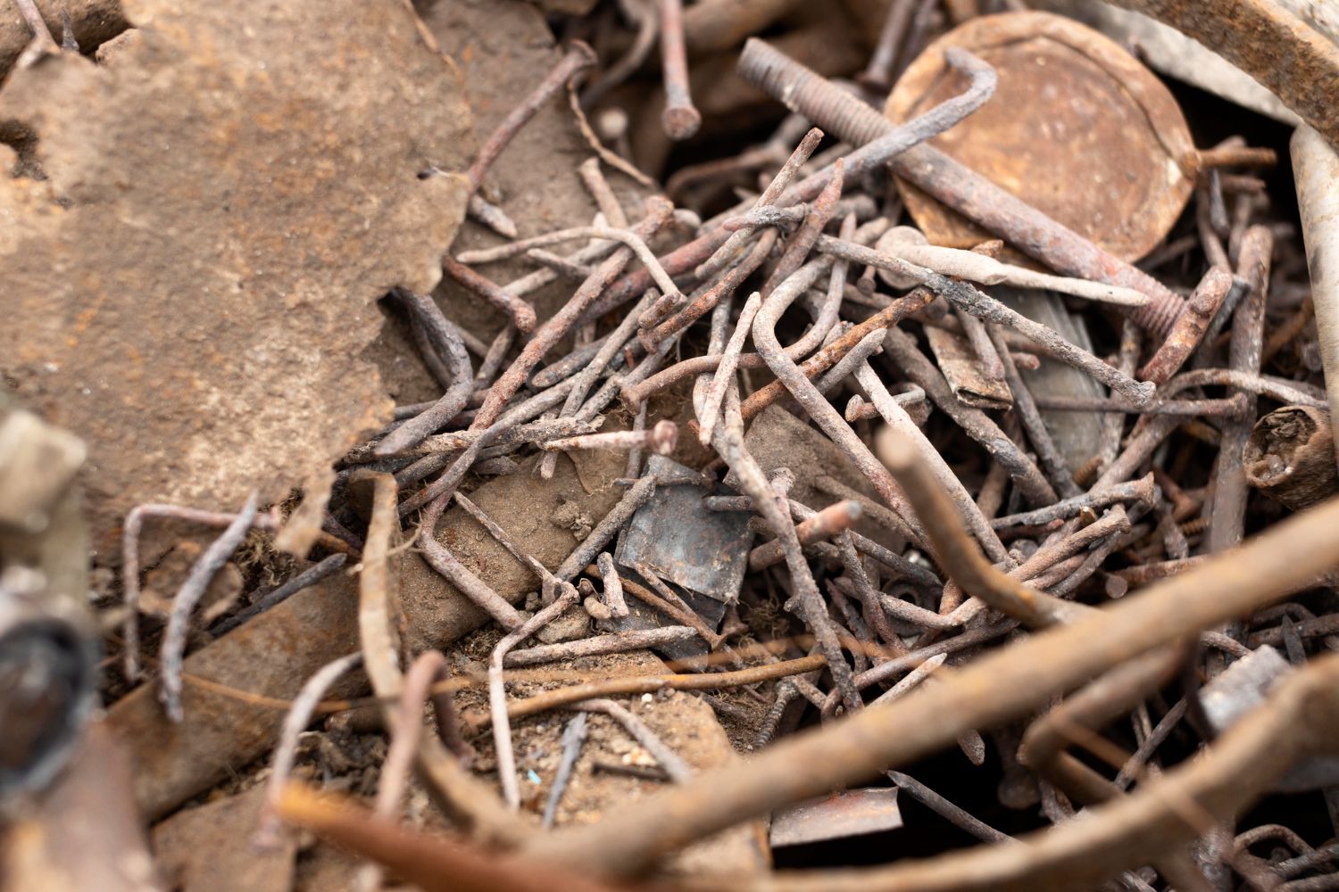 A pile of rusty wires and nails on the ground.