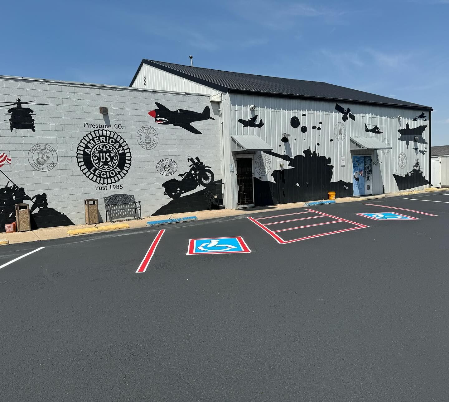 Mural-covered building with a parking lot, including a blue handicap space and red-striped access aisle