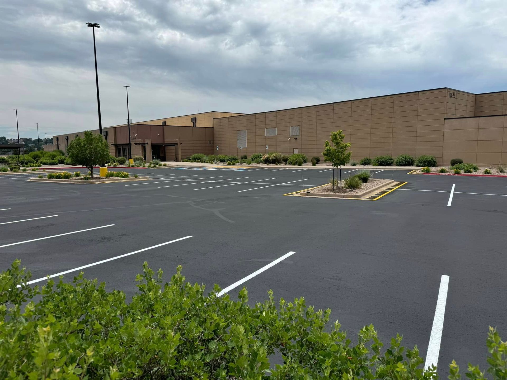 Empty parking lot beside a tan brick building under a cloudy sky