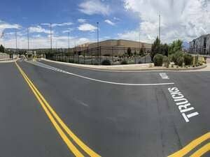 Wide road beside a beige building with yellow lines and a