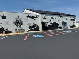Parking lot outside a white mural-covered building with marked accessible spaces and motorcycles painted on the wall
