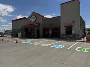 Accessible storefront with empty parking spaces and blue handicap spots under a clear sky