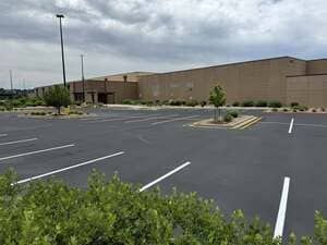 Empty parking lot beside a large brick commercial building under a cloudy sky
