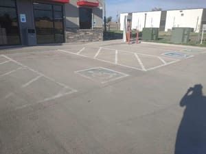 Empty accessible parking spaces marked on a paved lot beside a storefront