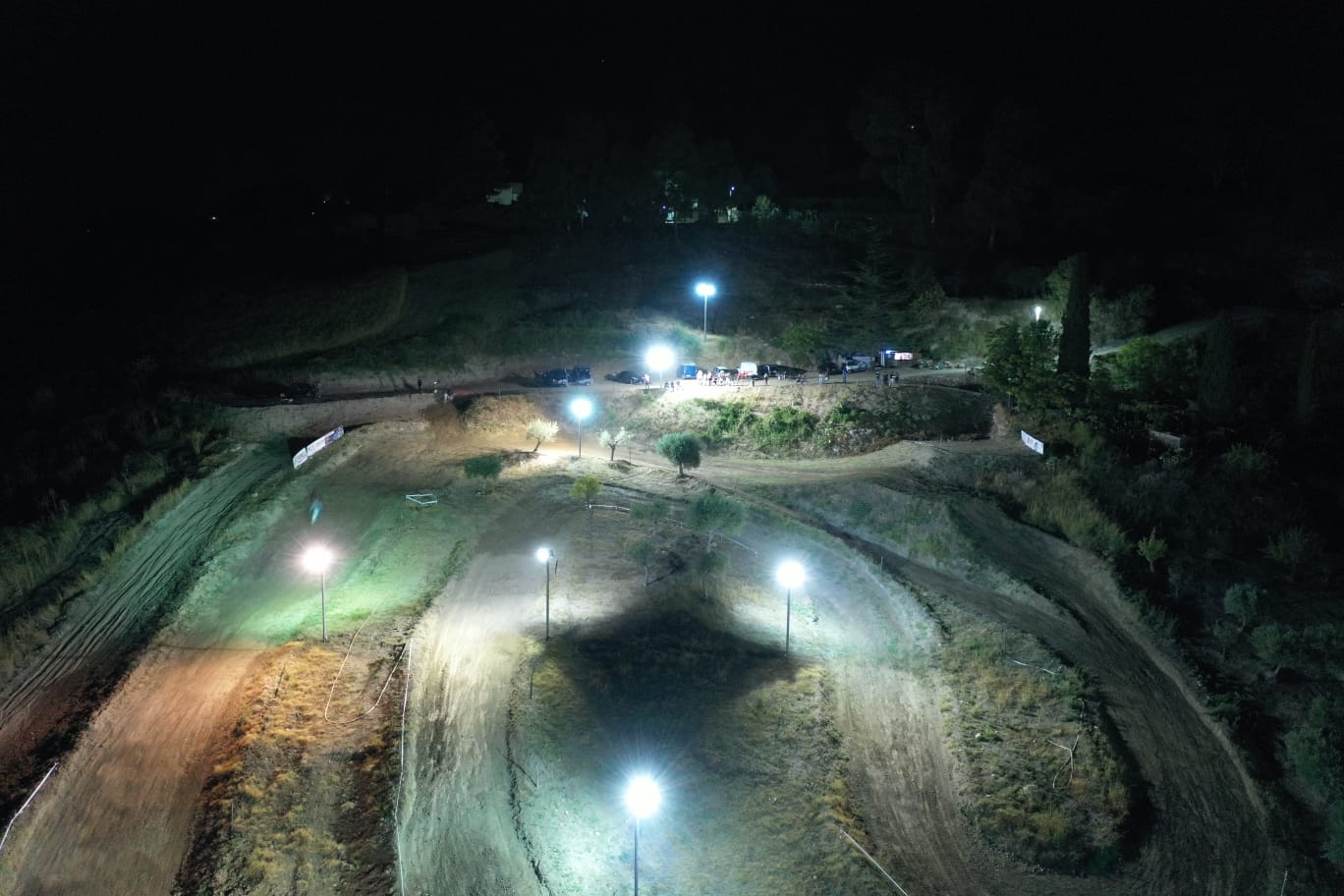 Pista da motocross notturna illuminata da luci intense. Percorso sterrato con numerose curve e salite.