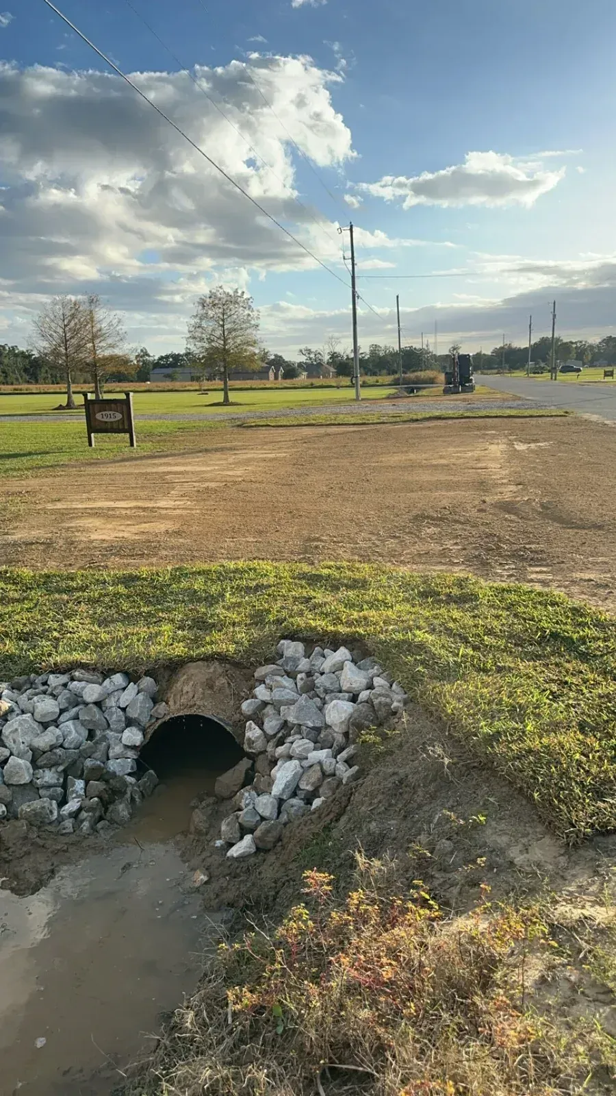 Installed driveway culvert pipe with rock headwall and restored grass entrance in Louisiana.