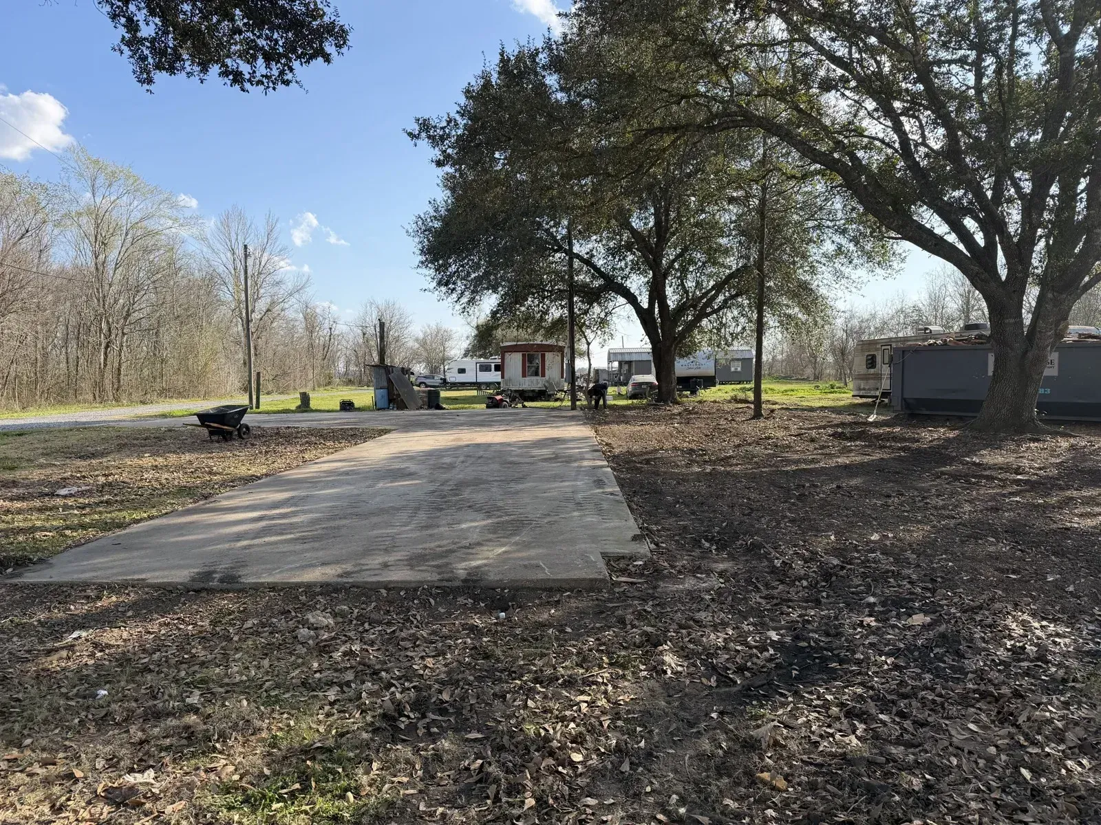 Cleared concrete foundation slab surrounded by oak trees after structure demolition.