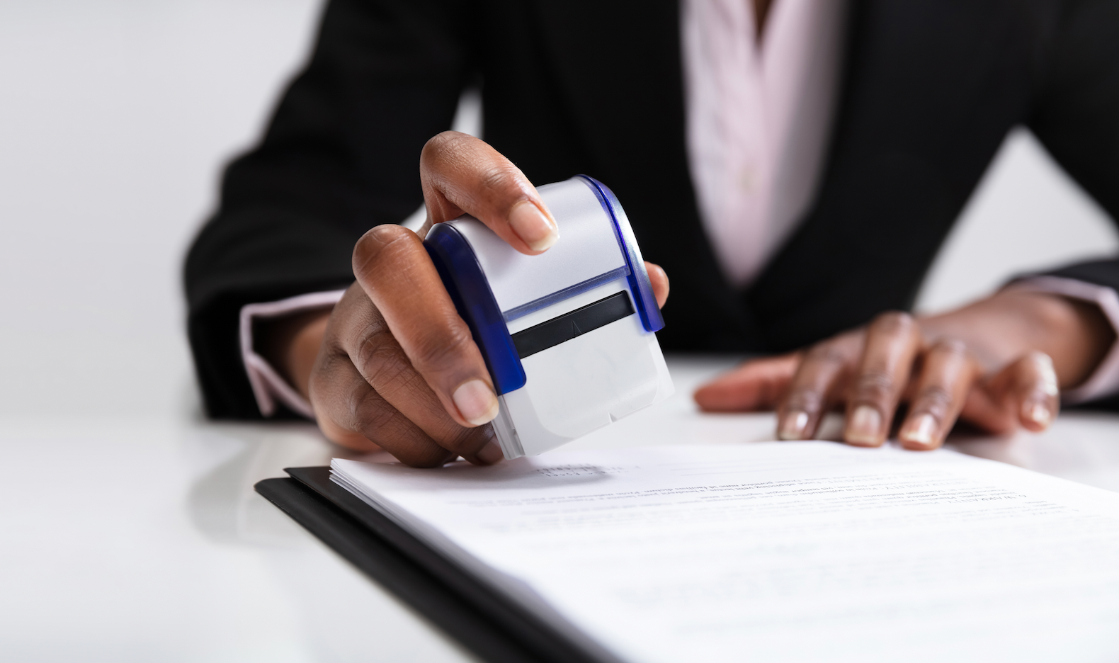 A person is signing a document on a clipboard next to a judge 's gavel.