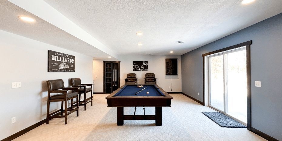 Bright game room with a pool table, bar stools, wall art, and sliding glass doors