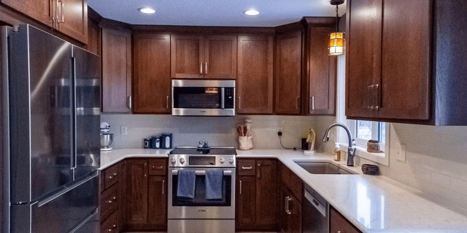 Modern kitchen with dark wood cabinets, stainless steel appliances, and a white countertop