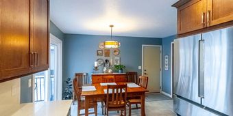 Bright kitchen with wooden dining table, cabinets, blue walls, and a stainless steel refrigerator