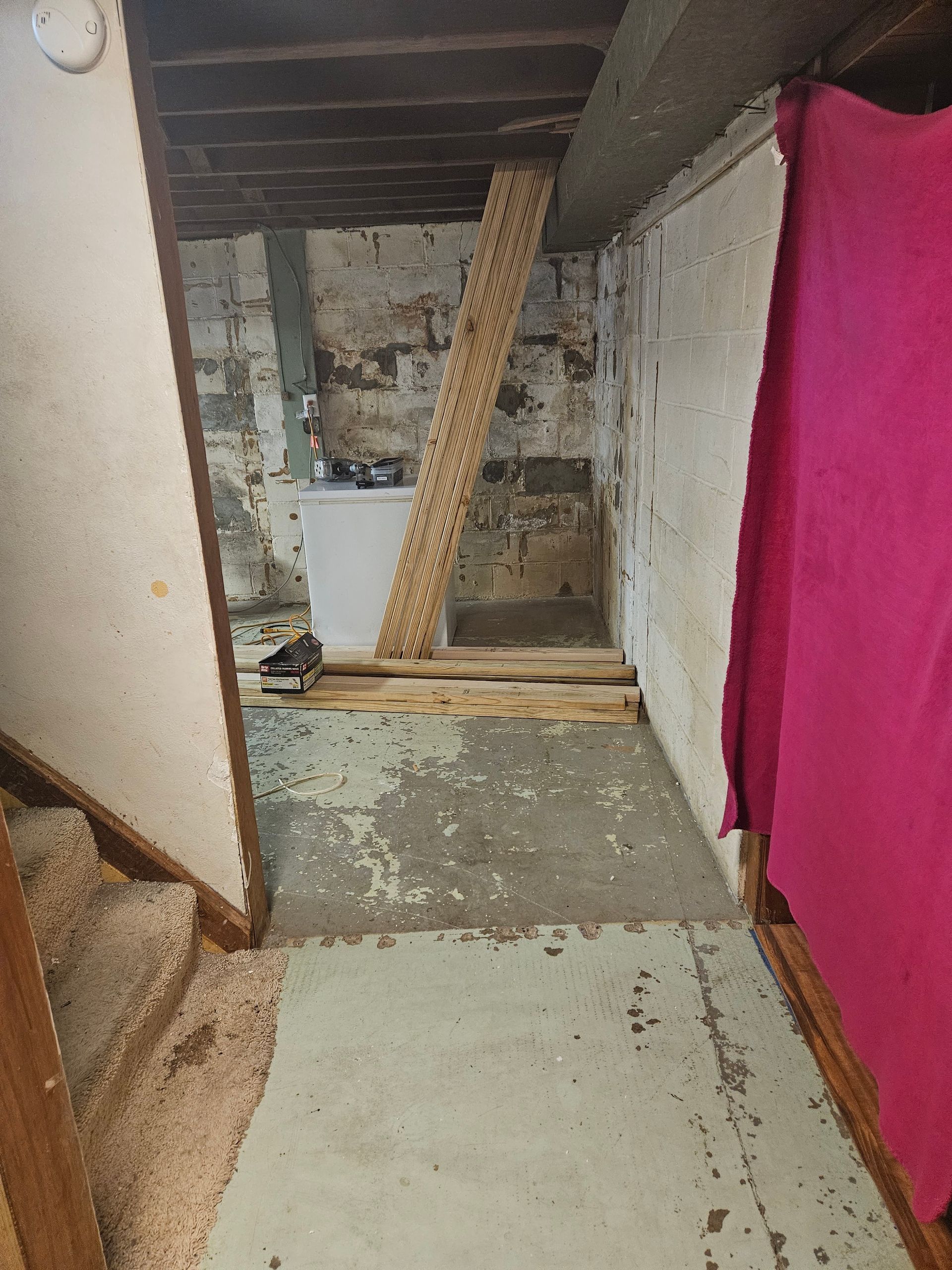 Narrow unfinished hallway with peeling walls, exposed ceiling, and a leaning wooden plank in the center.