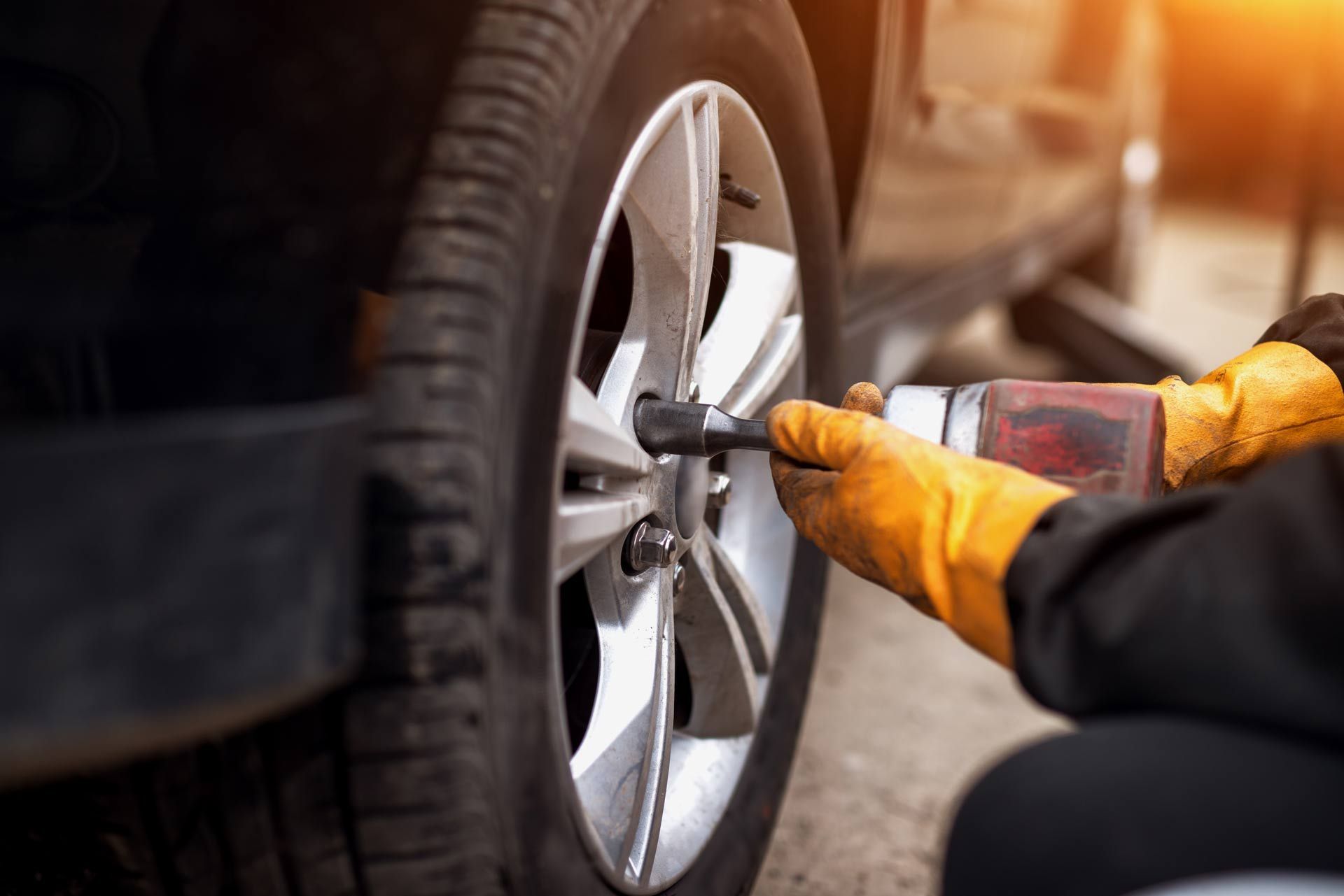 Auto mechanic man with electric screwdriver changing tire outside. Auto mechanic man with electric screwdriver changing tire outside.