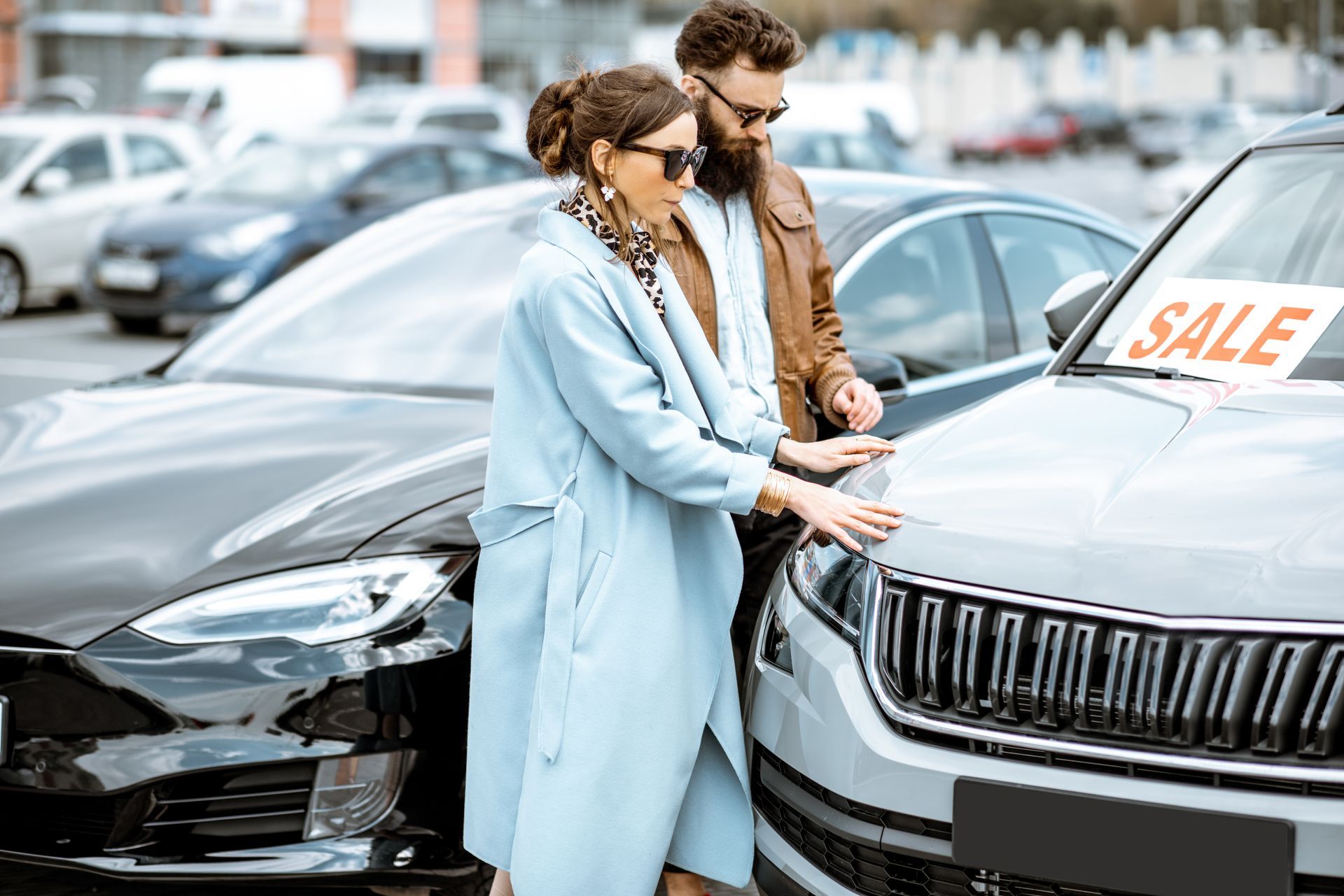 A couple choosing a car to buy on the open ground of a dealership.